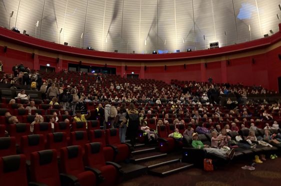 en stor gruppe mennesker som sitter i et stort auditorium