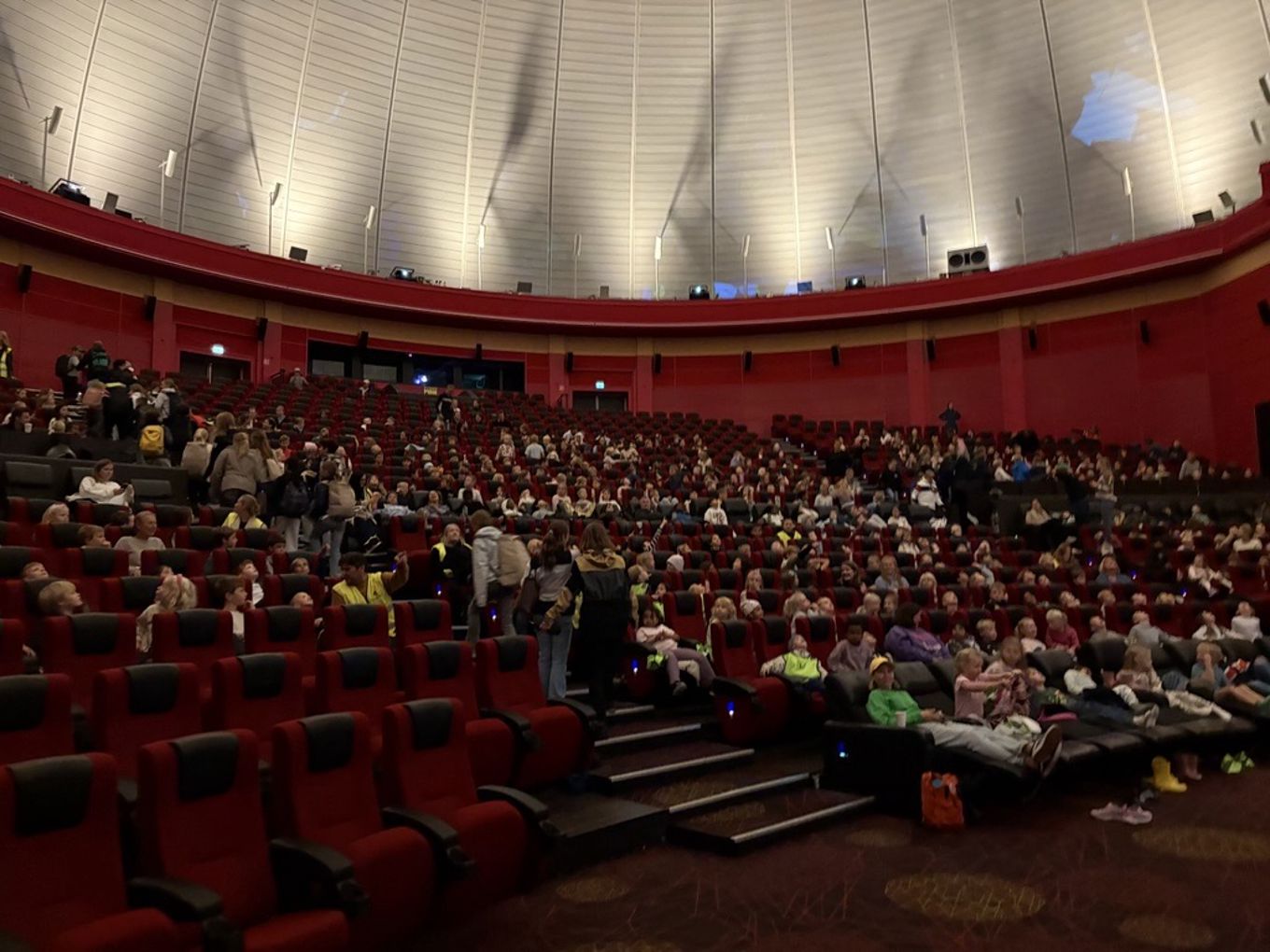 en stor gruppe mennesker som sitter i et stort auditorium