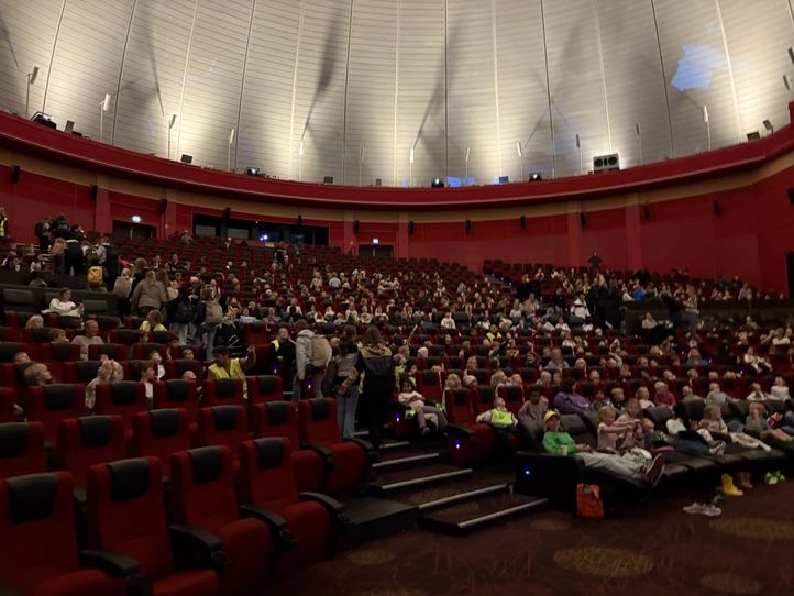 en stor gruppe mennesker som sitter i et stort auditorium