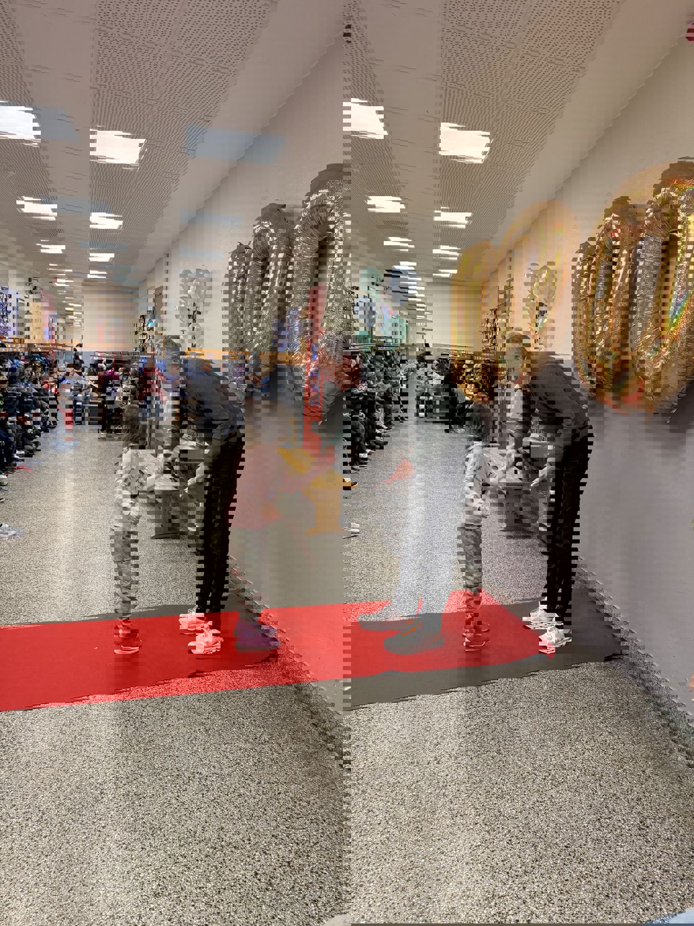 en person og et barn som står på en rød løper i et rom med en stor statue